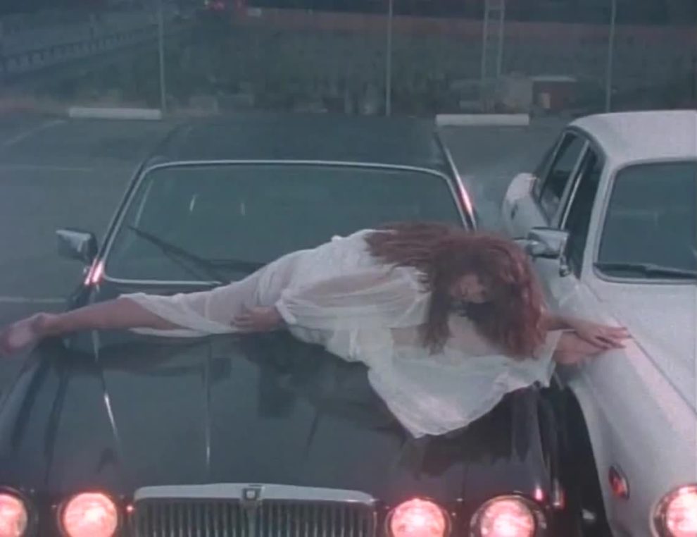 Tawny Kitaen on the hood of a car with some classic 80's music video plot